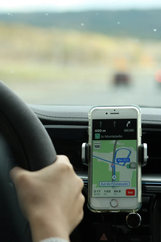 someone's hand on a phone while driving a car