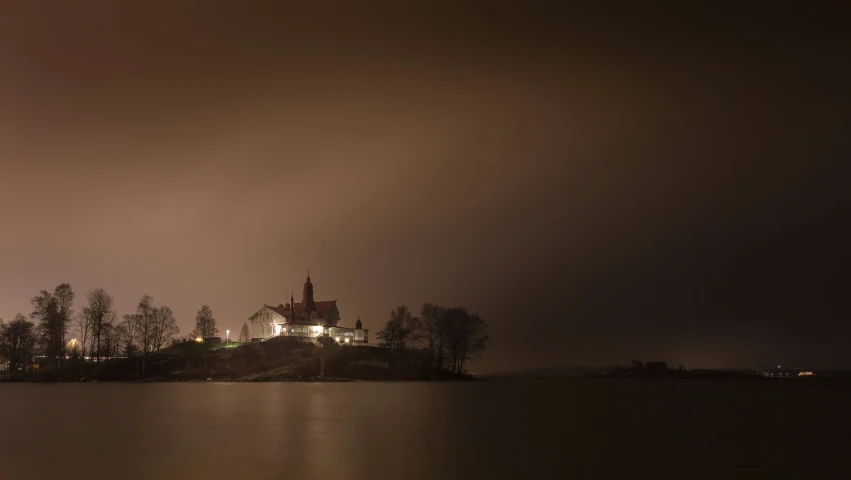 a house is sitting on a hill near a body of water