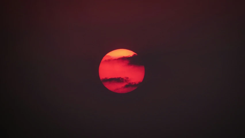 a red disk that has some clouds and a sky in the background