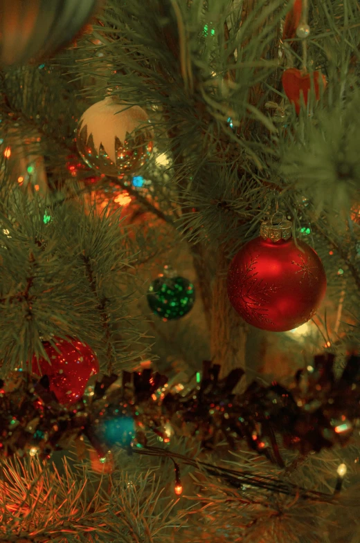 a christmas tree with red ornaments and blurry lights