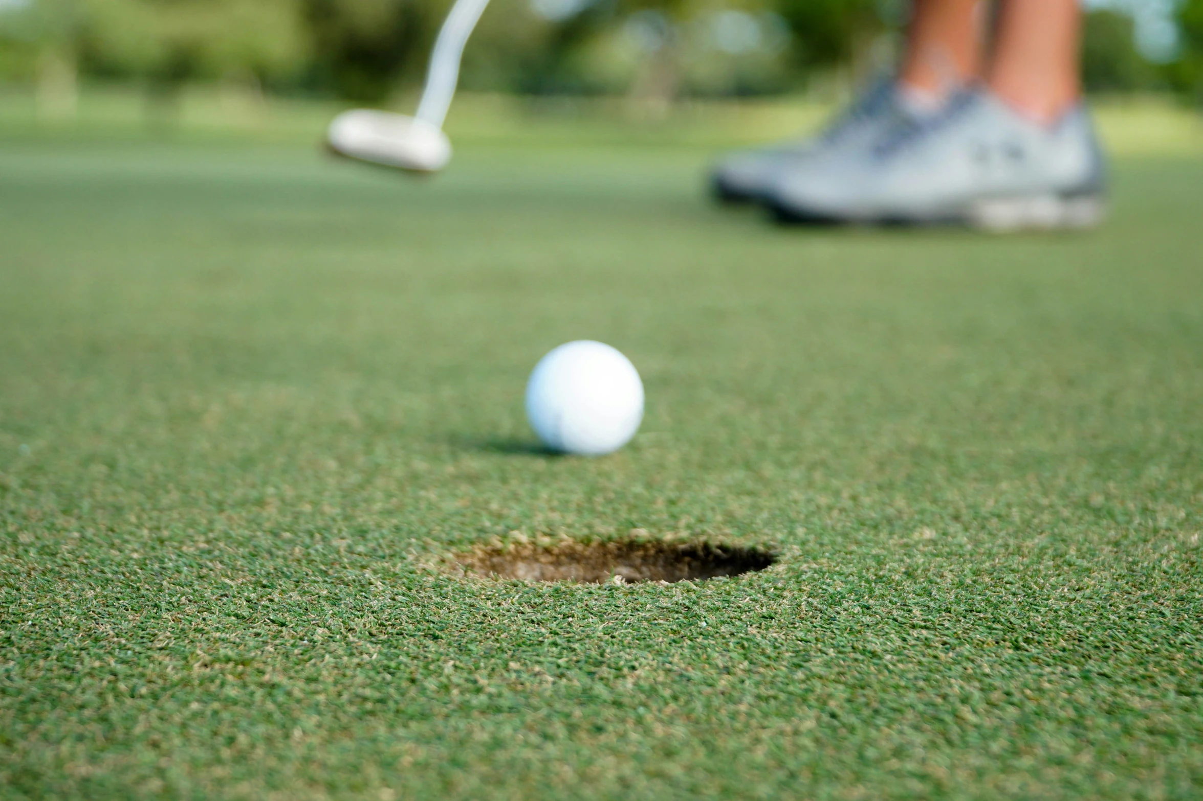 a golf ball in the hole near a person's foot