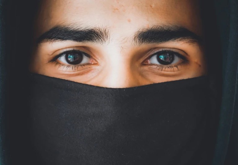 a person with blue eyes has a black covering over his head