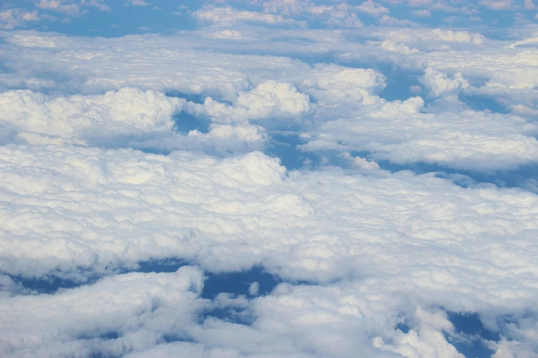 an airplane flying above some clouds that are mostly blue