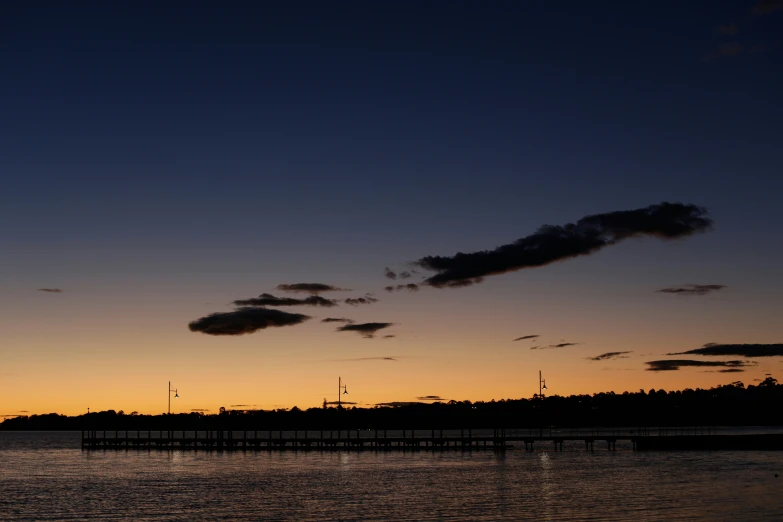 a beautiful sunset behind the water and a pier