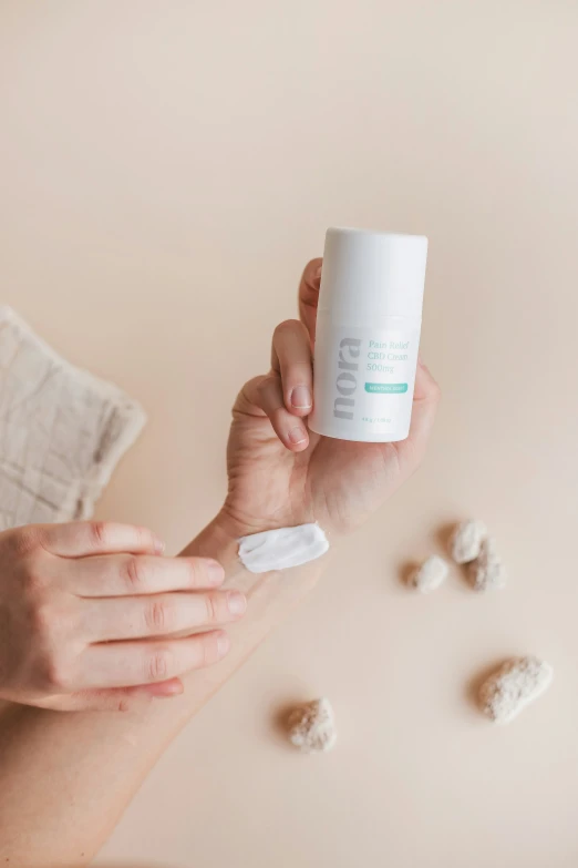 a person holding up a bottle of hand sanitizing cream