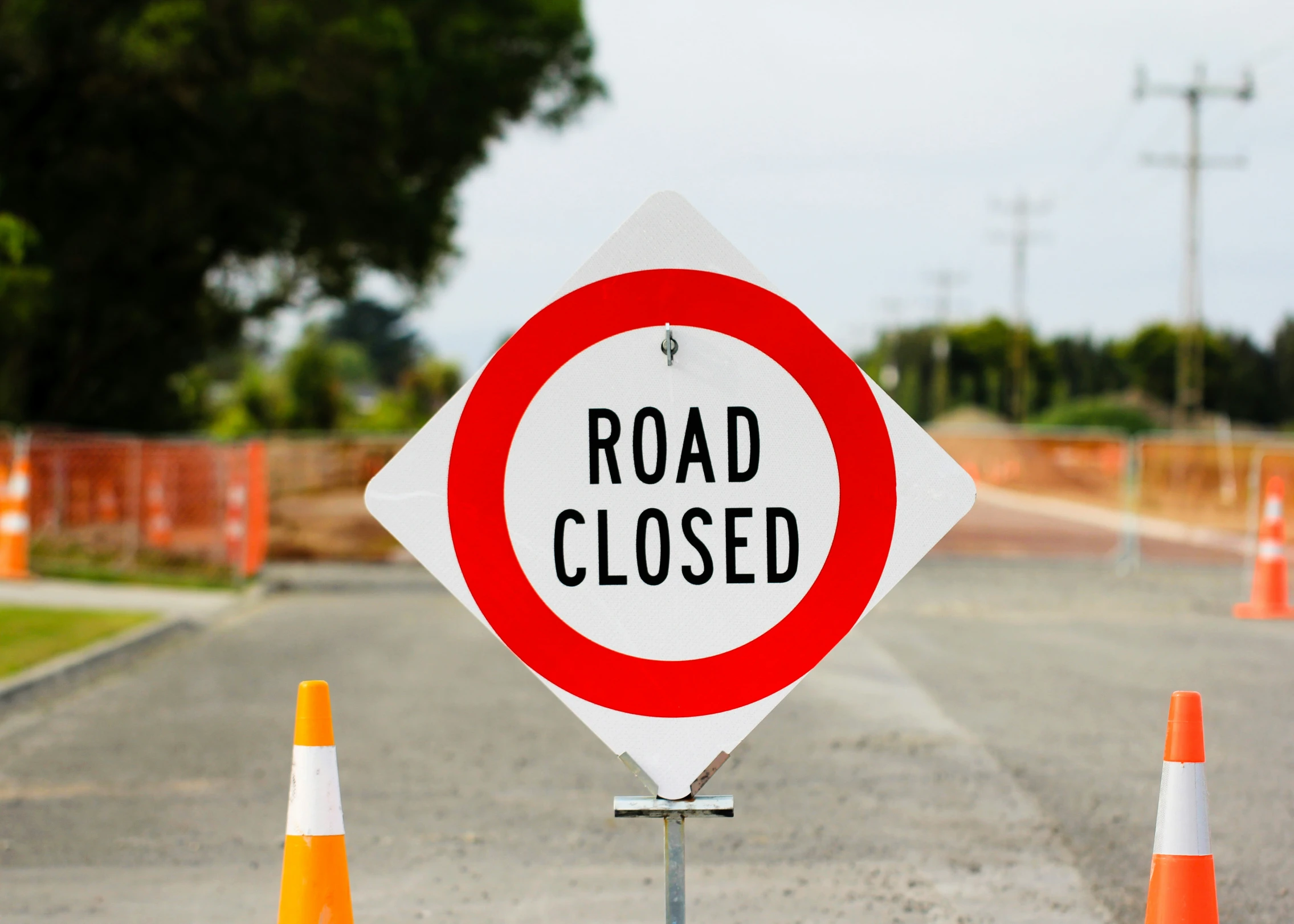 a road closed sign with an orange and white barricade