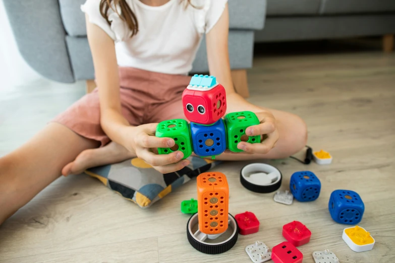 a  holding a building block with other blocks and a small toy