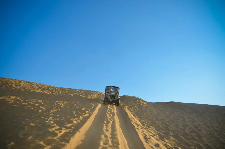 there is a suv in the middle of a sand dune
