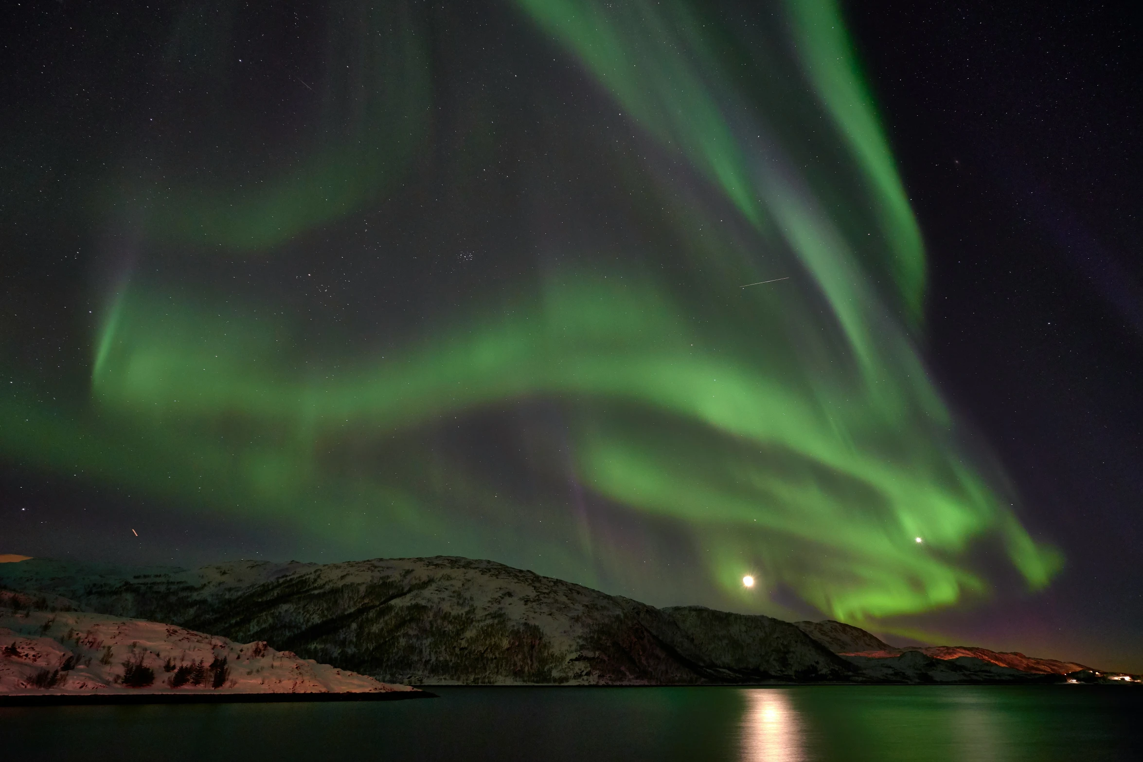 a bright green light shines in the night sky over a lake