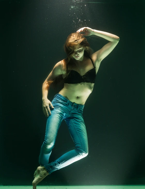 a woman standing underwater wearing blue jeans