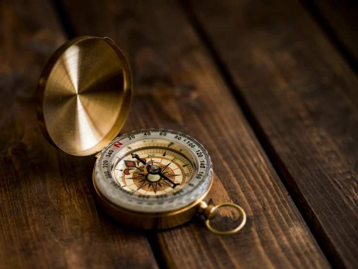 there is a gold compass on the wooden table