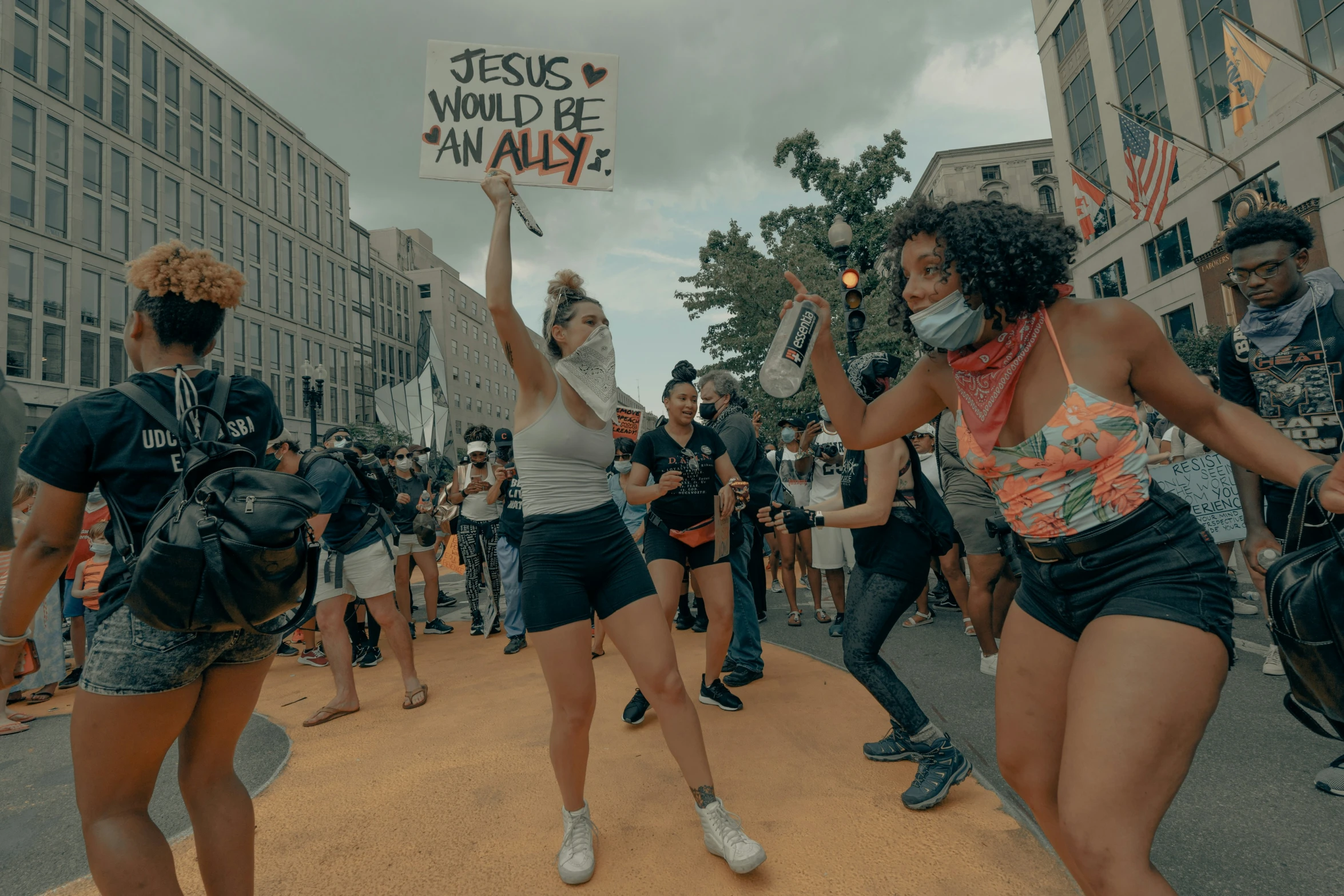 some women dancing with a sign that reads jesus would be wall