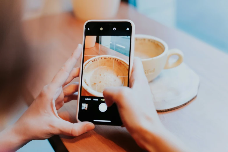 a person taking a picture of some coffee