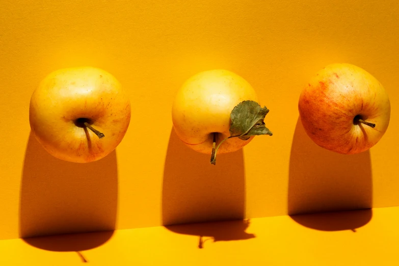 three apples are shown against a yellow background