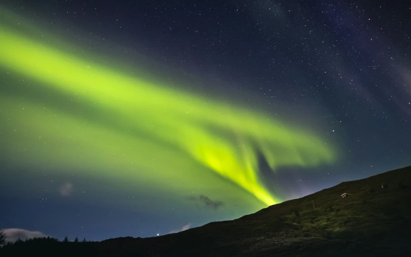 the aurora lights and a hill silhouetted against the night sky