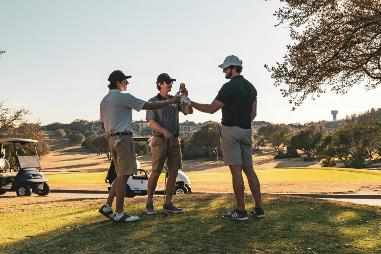 three men are standing on the grass shaking hands