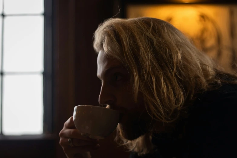 a bearded man drinking a cup of coffee