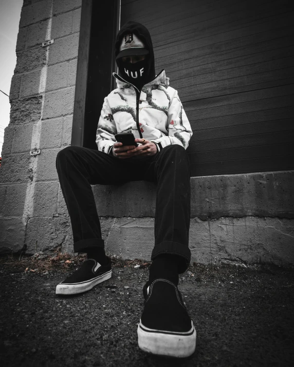 a man sitting on concrete next to a building