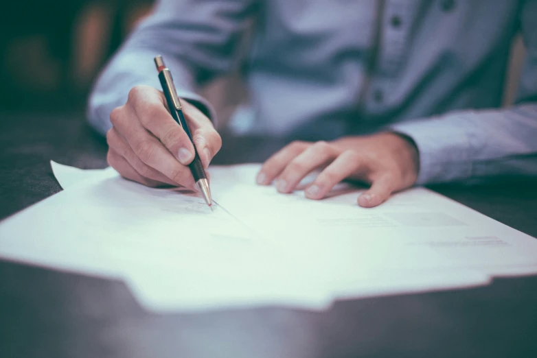 a man sitting at a table and signing papers