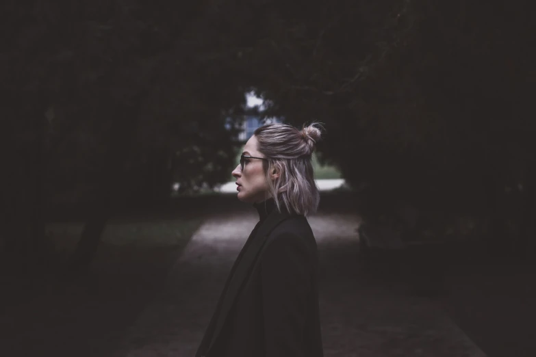 a young woman with her hair in a high bun, standing in front of a road