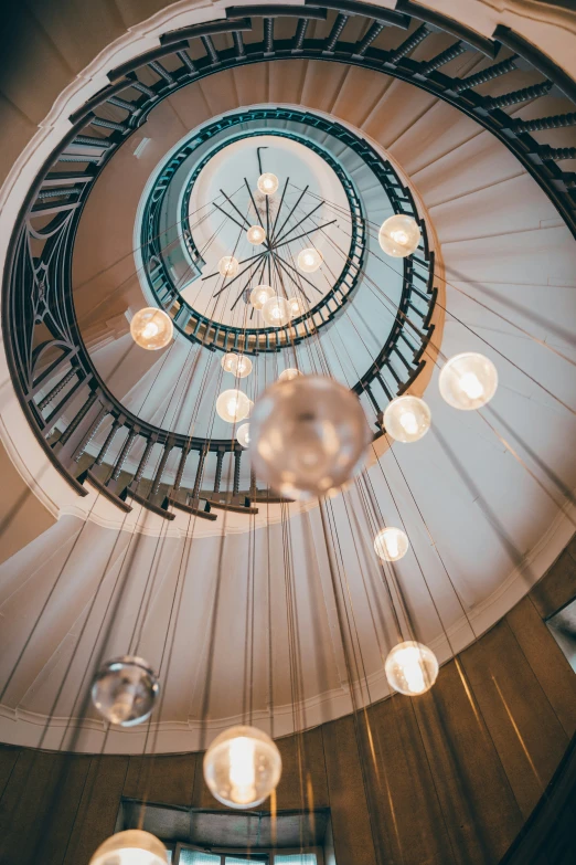 a bunch of lights hang from a round stair