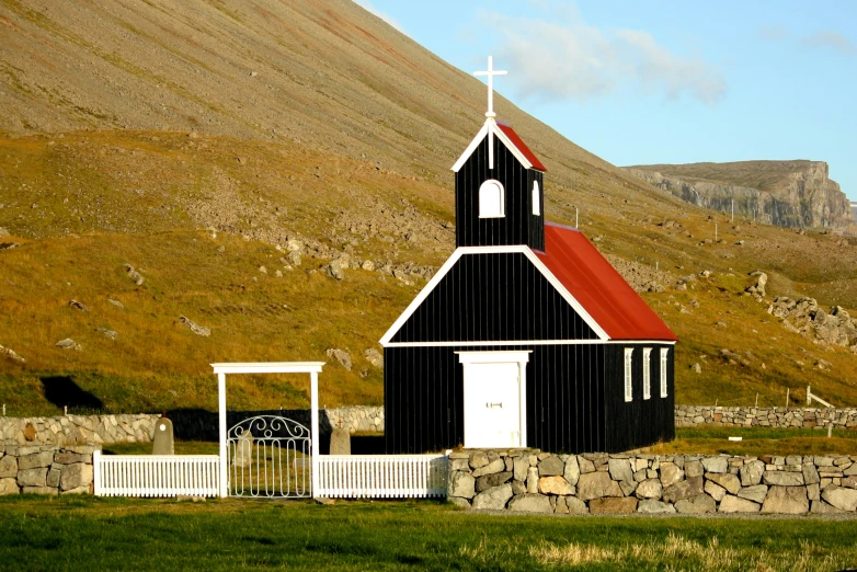 an old church on the side of the mountain with an iron gate and gate on it