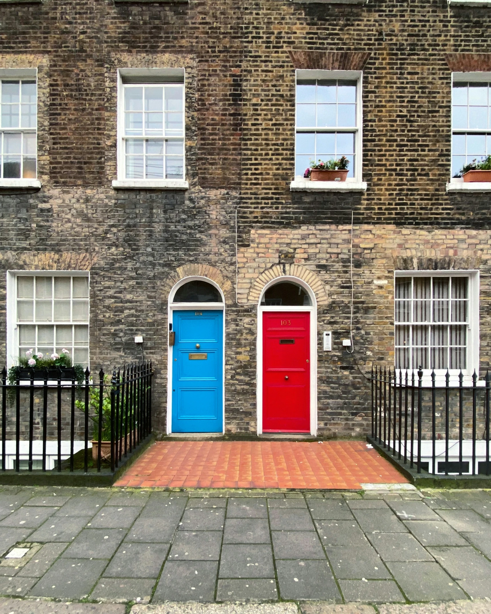 the house with two red doors is in front of a black fence