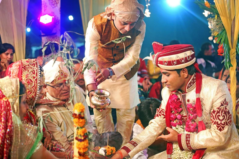 a couple standing in front of a small tree with a knife and an indian man touching the woman