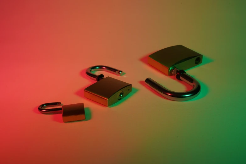 three locked padlocks are seen against a red, green and pink background