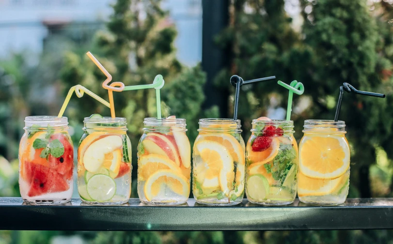 six jars of sliced fruits, limes, strawberries and bananas