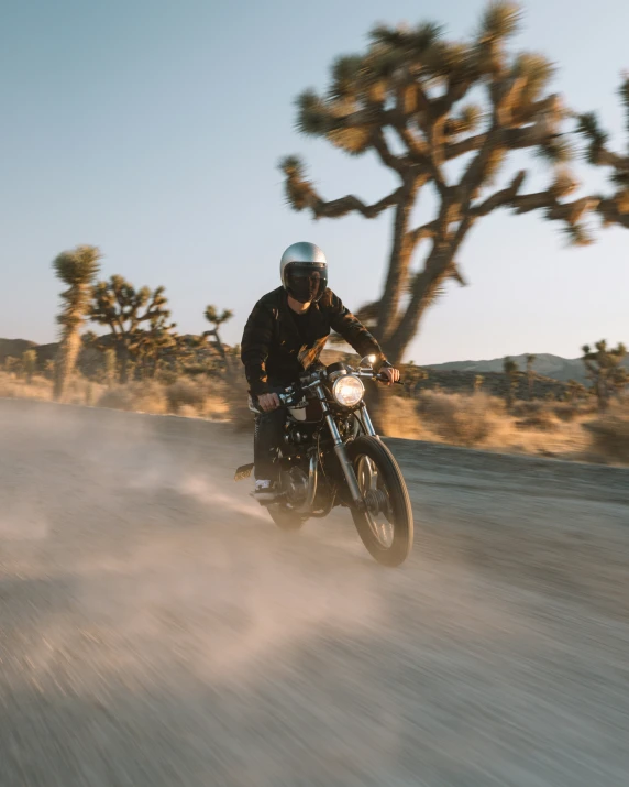 a man in leathers riding a motorcycle through the desert