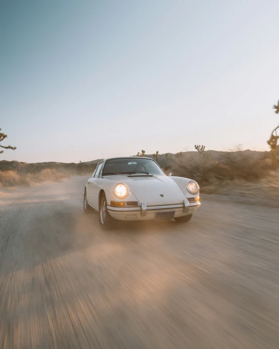 a white porsche is driving down the dirt road