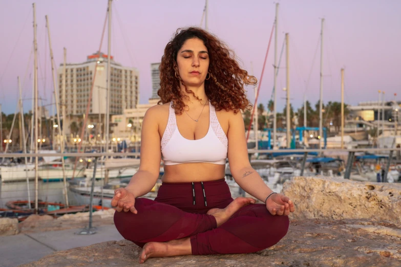 woman in yoga position near boats and the sea