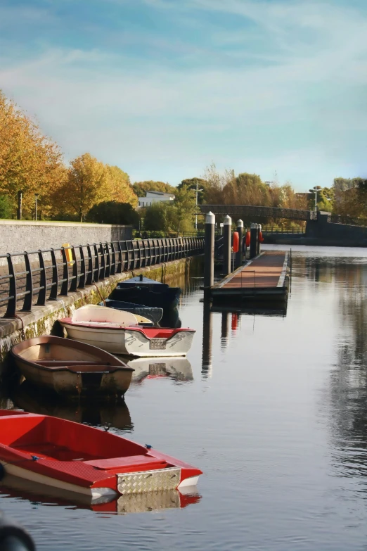 several boats sit in the still water near a dock