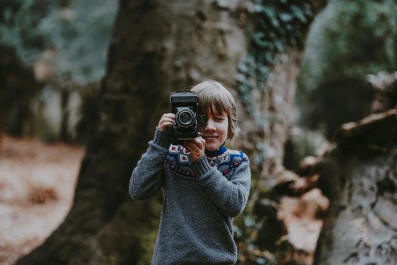 a little boy that is holding up a camera