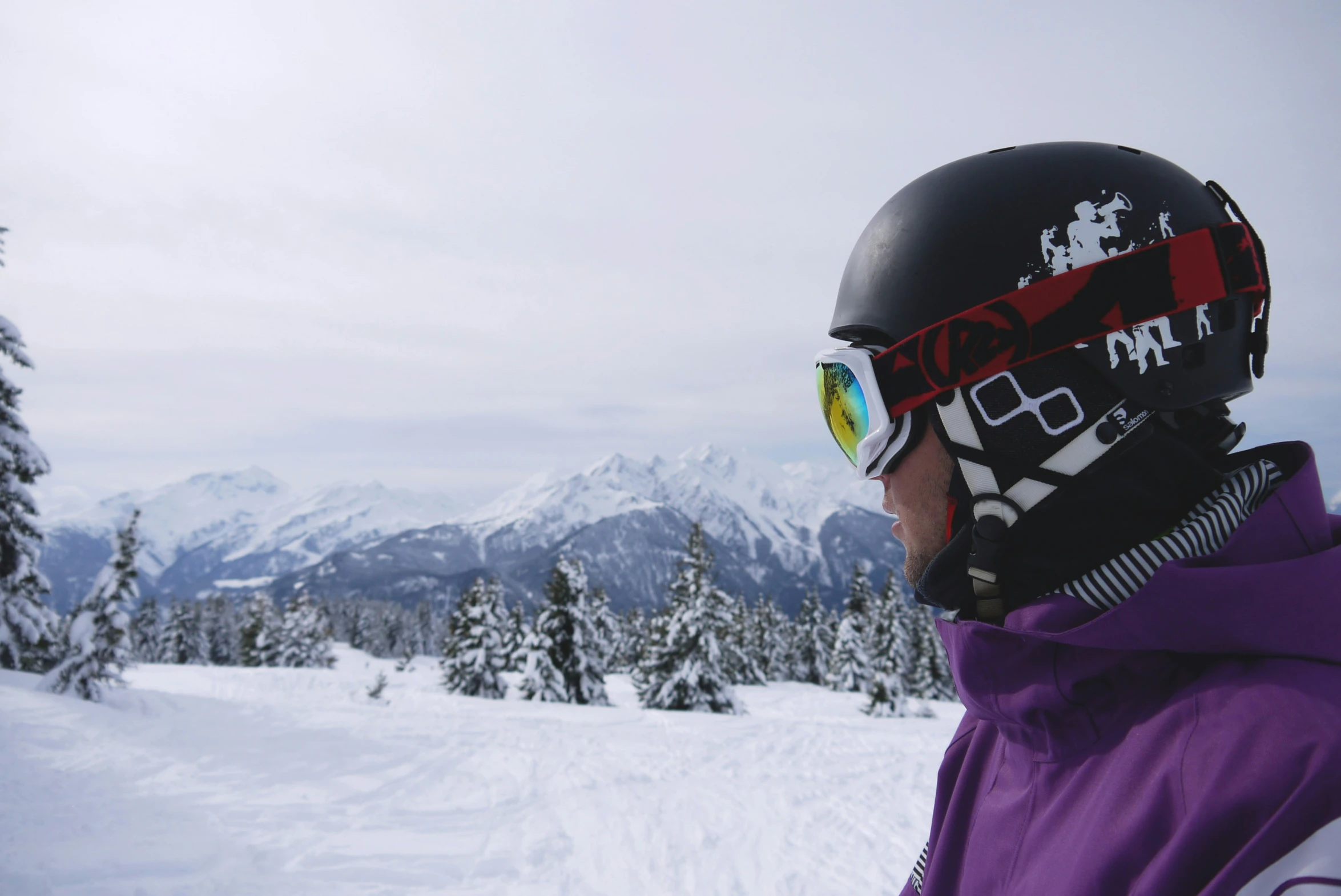 a man with ski goggles and a helmet on standing in the snow