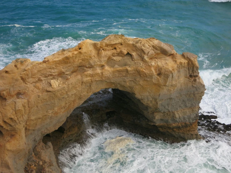a rocky cliff with an opening in the ocean