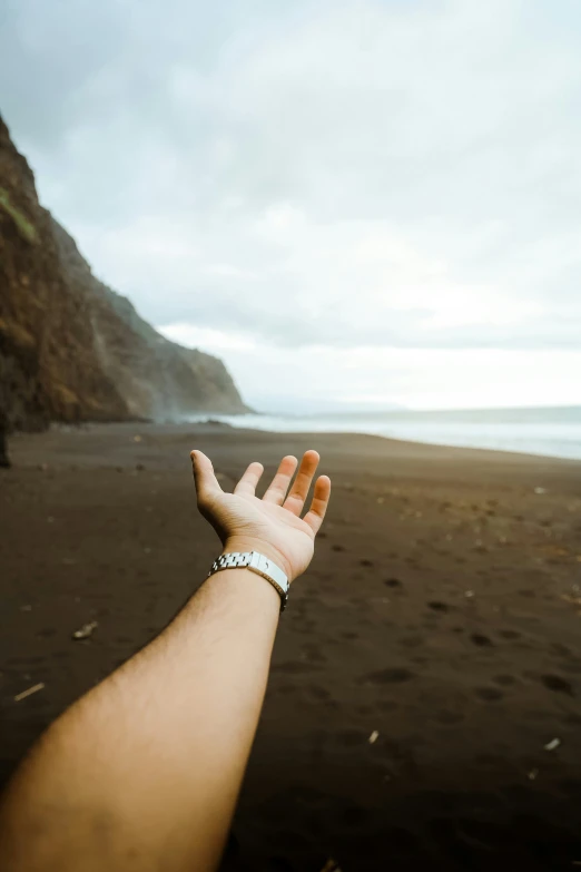 the hand of a person on a beach is reaching for the sky