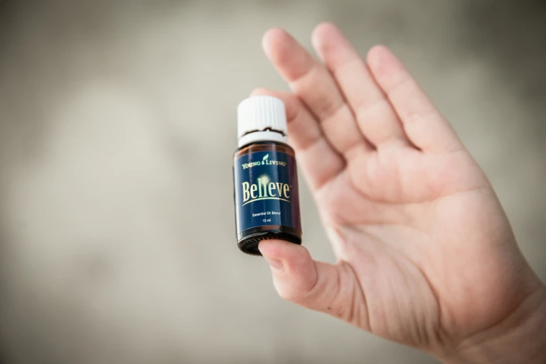 an open hand holding a small bottle filled with essential oils
