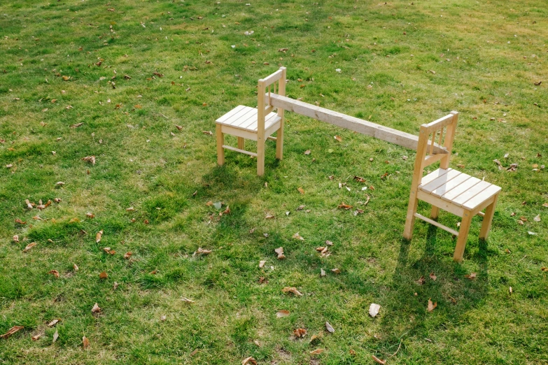 two wooden chairs in the grass on either side of a small bench