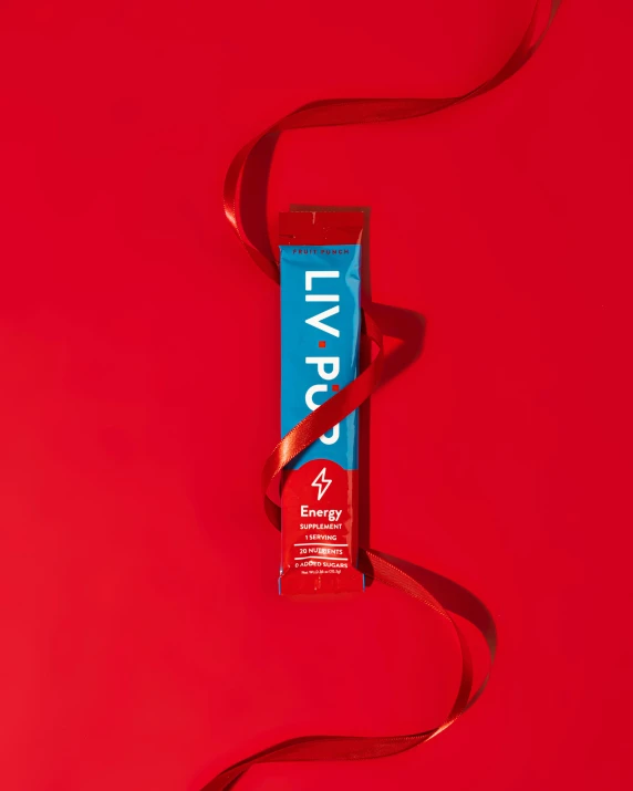 an unopened tube of toothpaste sitting on a red surface