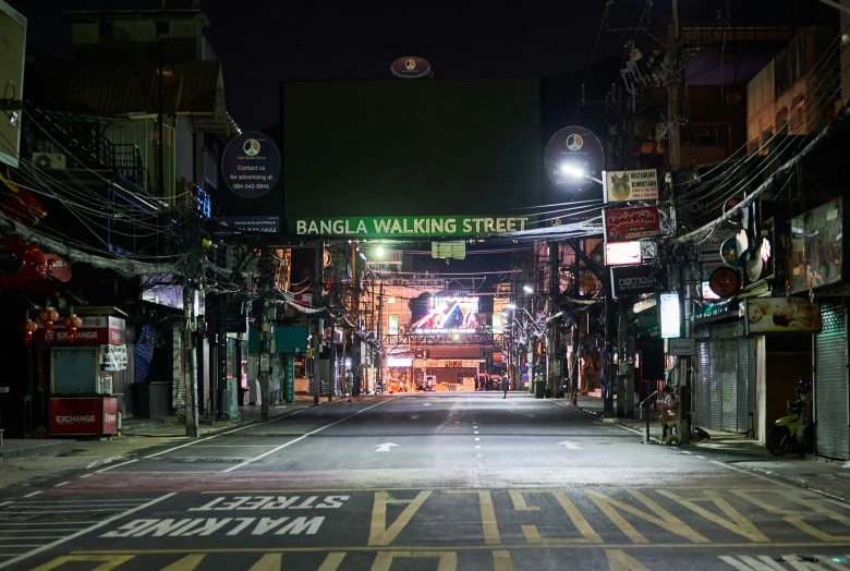 an empty street in a dark city with signs that say bangla walking street