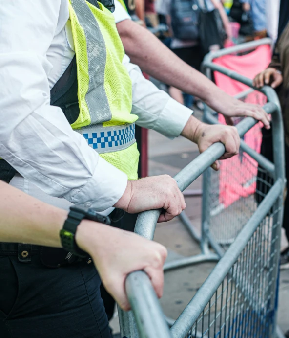 police officer in uniform stands at the railing near children in crowd