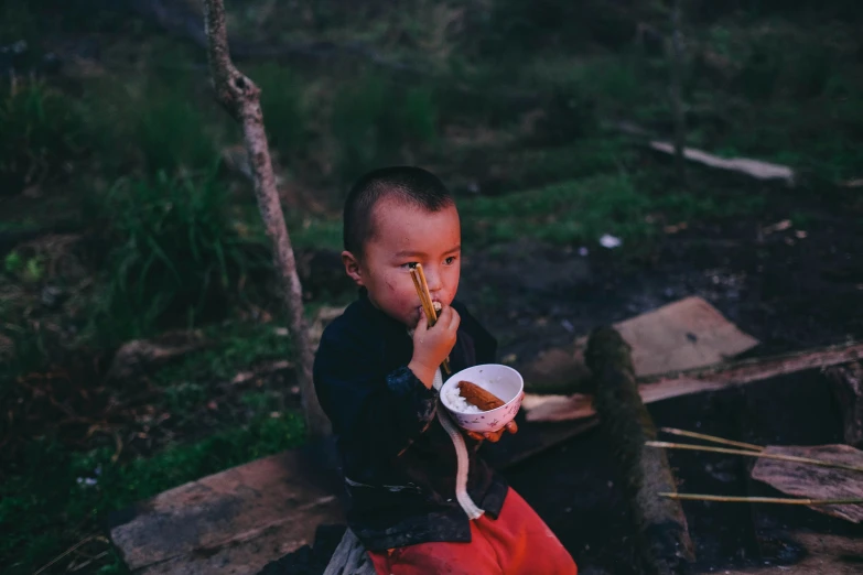 a  sitting on the ground eating from a plate