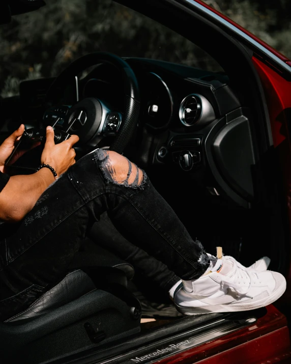 a guy sitting on his red car inside