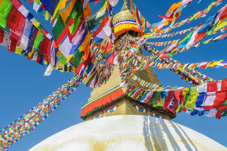 buddhist flags hanging from a large pole against a blue sky