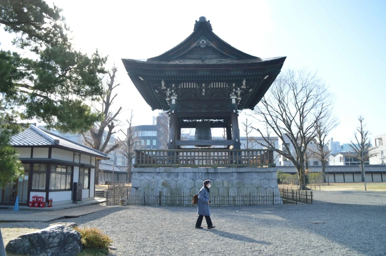 a girl standing under a pagoda in a city park