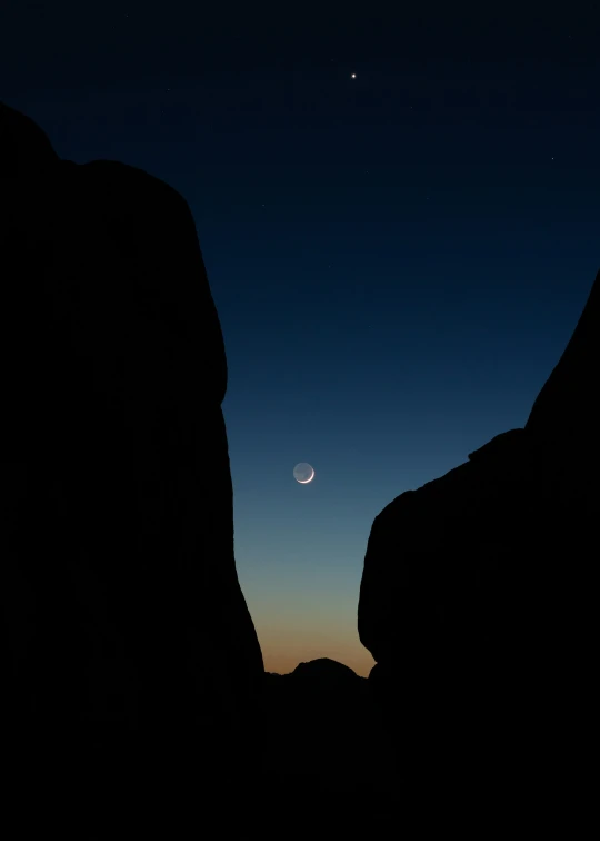 a view of the moon through some rocks