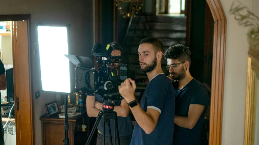 a camera operator holding a dslr with two men nearby