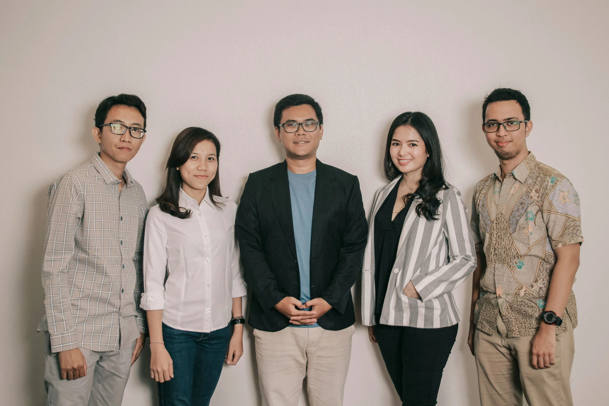 an asian group stands next to each other against a white wall